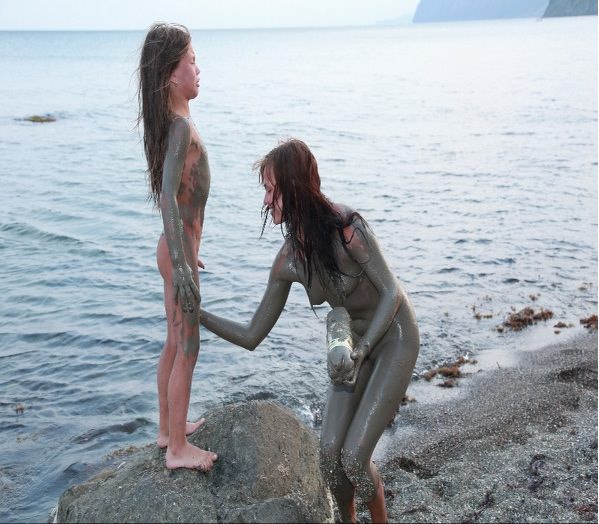 Nudists on the sea are smeared with medical dirt